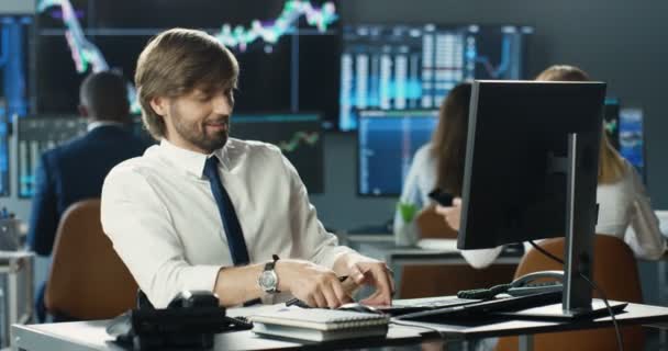 Caucasico bel giovane broker che lavora al computer in ufficio commerciale. Maschio manager digitando sulla tastiera. Trader mettendo scommesse e tassi su stock markt online. Seguire le tendenze. — Video Stock