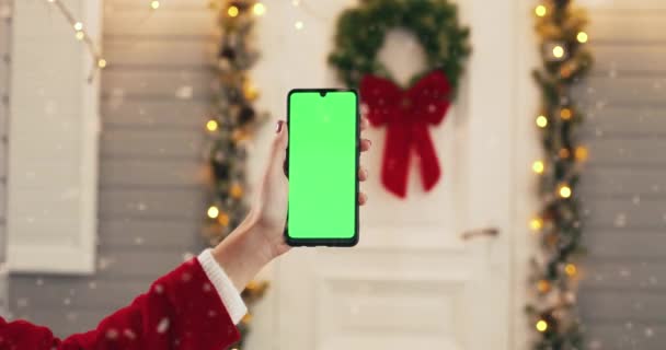 Close up shot of Caucasian female hand holding black smartphone with green screen while standing outdoors on New Year Eve. Cellphone with chroma key in woman hands on Christmas. Technology concept — Stock Video