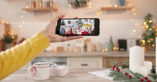 Gros plan de l'écran de téléphone portable avec plusieurs appels vidéo en ligne avec des amis américains Afican multi-ethniques et des parents caucasiens à la main féminine la veille du Nouvel An à la maison Joyeux Noël célébration — Video