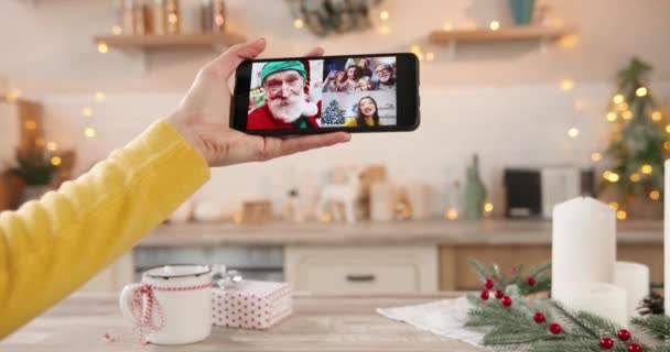Primo piano dello schermo dello smartphone con più chiamate online tra il vecchio vestito da Babbo Natale e i giovani amici multietnici asiatici e caucasici che mandano saluti a Natale. Vacanze invernali — Video Stock