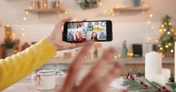 Primo piano dello schermo dello smartphone con videoconferenza multipla con amiche e parenti asiatici e caucasici multietnici a casa decorata in quarantena. Capodanno. Buon Natale. Ciao.. — Video Stock