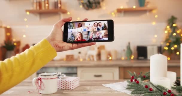 Закрыть смартфон онлайн-конференц-видео с разными людьми. Многочисленные видеозвонки с друзьями-мужчинами и женщинами и старым белым папочкой в костюме Санты в канун Рождества. Новый год — стоковое видео