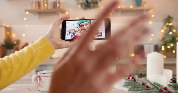 Fechar a tela do smartphone com bate-papo de vídeo online com pessoas diferentes. Mulher mão segura celular falando em várias chamadas de vídeo com a família e parentes na véspera de Natal. Celebração de Ano Novo — Vídeo de Stock