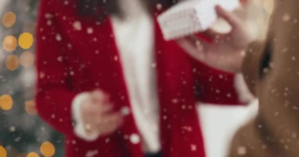 Primo piano di uomo caucasico premuroso mani dando regalo di Natale alla donna amata a Natale sulla strada innevata all'aperto. Ricezione femminile e tenuta avvolta presente nelle mani sul concetto di regali di Natale di Capodanno — Video Stock