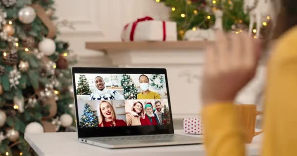 Mujer saludando de la mano y hablando en múltiples chat de vídeo en el ordenador portátil con las razas mixtas afroamericanos y caucásicos amigos en la Navidad de buen humor. Primer plano de videochat femenino en el ordenador — Vídeos de Stock