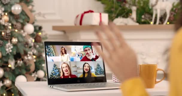 Zamknij drzwi. Przez ramię widok kobiety machającej ręką i wideo na laptopie z radosnymi przyjaciółmi i staruszkiem na Boże Narodzenie. Wielokrotny telefon między przyjaciółmi i krewnymi w Nowy Rok. Koncepcja urlopu — Wideo stockowe