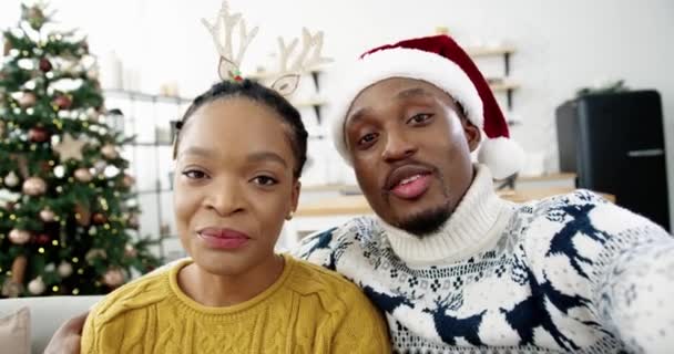 POV de feliz afroamericano hombre y mujer pareja en casa con decorado árbol de navidad en línea video chat y saludos de vacaciones a amigos y familiares. Nochebuena. Espíritu de vacaciones — Vídeos de Stock