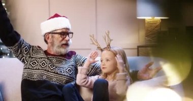 Mutlu beyaz aile portresi. Küçük şirin bir torunu olan yaşlı büyük baba. Yılbaşı arifesini birlikte geçirip konuşarak geçirdikleri Noel ağacının yanındaki süslü odada oturuyor. Kış tatili kavramı