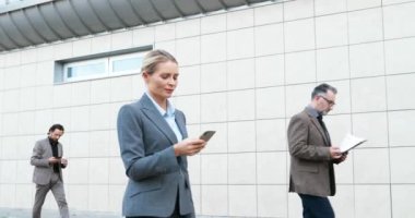 Kafkasyalı genç iş kadını elinde aletlerle sokakta yürüyor. Karışık ırk erkek ve kadın yayalar dışarıda geziniyor ve cihazlar kullanıyorlar. Çok ırklı iş adamları şehirde çalışmaya can atıyorlar.