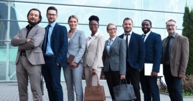 Melez iş adamları ve iş kadınlarının açık havada yan yana durup kameraya gülümseyişlerinin portresi. Çok ırklı iş adamları ve kadın ortaklardan oluşan bir ekip. Uluslararası yatırımcı grubu.