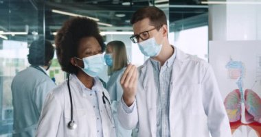 Klinikte durup Coronavirus enfeksiyonu aşısı hakkında konuşan, tıbbi maskeler takan çok ırklı kadın ve erkek doktorların portresi. Sağlık konsepti. covid19 salgını