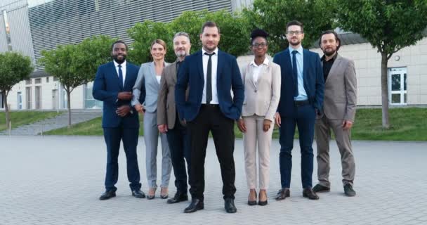 Portret van succesvolle jonge blanke mannelijke baas met een team van multi-etnische mannen en vrouwelijke collega 's. Mixed-races zakenmannen en zakenvrouwen glimlachend naar de camera buiten. Collega 's. — Stockvideo