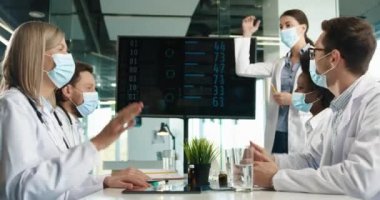 Hastane ofisindeki maskeli melez doktorlar koronavirüs salgını sırasında tedavi sonuçlarından memnun kalarak beşlik çakıyorlar. Covid-19 'la savaşan mutlu sağlık çalışanları. Hastalık konsepti