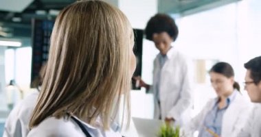 Kameraya çekilen mutlu yaşlı kadın doktor portresini yakın çekimde erkek ve kadın doktorlarla Pulmon hastalığı covid-19 hakkında konuşurken gülümsüyor. Coronavirüs salgını konsepti