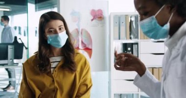 İş yerindeki tıbbi maskeli Afrikalı Amerikalı kadın doktor portresi. Kadın hastaya tıbbi danışmanlık yapıyor ve ilaç tedavisi uyguluyor. Coronavirus enfeksiyonu konsepti