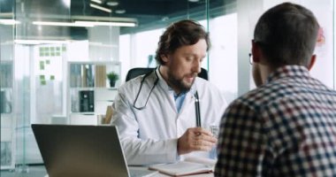 Dolabın içinde doktorla görüşen erkek hastaların geçmişine bakıyorum. İşteki yakışıklı bir doktorun hastayla konuşurken ve tıbbı gösterirken çekilmiş portresi. Sağlık hizmetleri kavramı