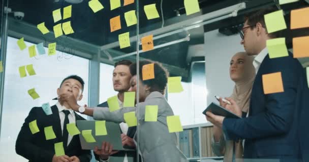 Retrato del equipo de vendedores profesionales masculinos y femeninos que trabajan en la oficina moderna del gabinete y escriben en tablero de cristal usando el dispositivo de la tableta, hablando y discutiendo el proyecto de negocio. Concepto de trabajo — Vídeo de stock