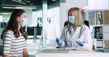 Tıbbi maskeli kıdemli kadın doktorun portresi. Genç beyaz kadın hastayla konuşuyor. Doktor muayenesinde hastanede oturuyor. Coronavirus konsepti. Kapsamlı salgın
