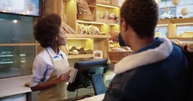 Afrikalı Amerikalı bir müşterinin fırından ekmek alıp pişirmesi. Pastanede taze ekmek satan güzel, mutlu, genç bir kadın satıcı. Küçük işletme kavramı