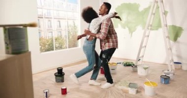 Afro-Amerikalı mutlu genç çift yeni bir apartman dairesinde sarılıp kucaklaşıyorlar. Neşeli aile çifti karı koca iyi ruh hali içinde yenileme evindeler. Geliştirme kavramı