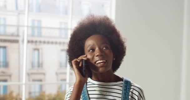 Close up of joyful African American beautiful female smiling and speaking on cellphone in apartment in good mood Happy woman calling on smartphone talk to handyman about home repair Renovation concept — Stock Video