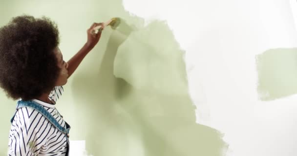 Primer plano de la hermosa mujer afroamericana pintando la pared en un apartamento nuevo usando pincel cansado de reparar el trabajo casa Casa redecoración y construcción de viviendas mientras se renueva y mejora — Vídeos de Stock