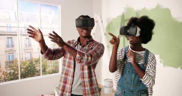 Portrait of joyful young African American married couple standing in room during home renovation wearing VR glasses looking at renewed apartment design using virtual reality futuristic technology — Stock Video