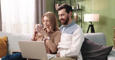 Genç, mutlu, beyaz bir ailenin portresi interneti araştırıyor, internette mesajlaşıyor ve internette internette geziniyor kanepede oturmuş çay ya da kahveyle ailece vakit geçiriyorlar..