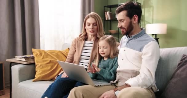 Joyeux Caucasiens jeunes parents de la famille et petit adorable enfant vidéochat parler sur appel vidéo en ligne sur ordinateur portable agitant les mains et souriant. Du temps en famille. Concept de maison — Video