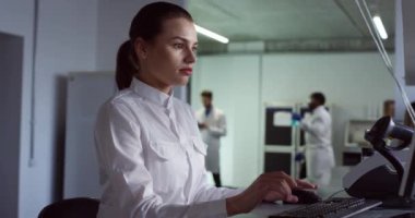 Beyaz tenli güzel kadın profesyonel laboratuvar asistanı ofisinde oturuyor ve analiz için klavyeye yazı yazıyor. İş yerindeki Portrede kadın mikrobiyoloji bilimcisi