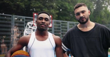 Çok ırklı basketbol oyuncularının sıkı antrenmandan sonra terlerini elleriyle silmelerine yakın çekim. Afrika kökenli Amerikalı ve Kafkasyalı sporcular maçtan sonra sahada duruyorlar. Şehir Portresi Sokak Topu konsepti