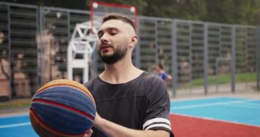 Basketbol sahasında dikilen neşeli yakışıklı erkek oyunculara ve şehirde parmak üstüne parmak çeviren toplara yakından bakın. Genç Kafkas sporcusu dışarıda topla antrenman yapıyor. Portre konsepti