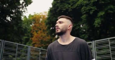 Şehir kortunda pratik yapan ve top atan yakışıklı beyaz bir sporcunun portresi. Sokakta sokak basketbolu oynayan erkek basketbolcu. Açık havada antrenman. Konsepti kapat