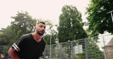 Beyaz tenli yakışıklı sokak basketbolcusunun şehir dışındaki oyun sahasında basketbol potasına top fırlatırkenki yakın portresi. Sahada tek başına sporcu eğitimi. Spor konsepti