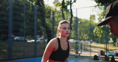 Açık havada sokak basketbolu oynayan çok ırklı gençlerin yakın portresi. Güzel beyaz kız ve Afrikalı Amerikalı erkek basketbolcular yerel kortta antrenman yapıyor ve oynuyor. Spor konsepti