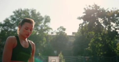 Beyaz tenli güzel bayan basketbolcunun dış sahada pratik yaptığı ve top attığı portreyi yakından çek. Şehir parkında sokak basketbolu oynayan kız. Eğitim kavramı