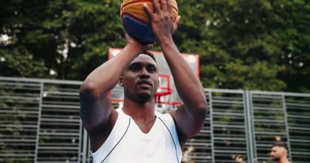 Close up portret przystojny młody Afroamerykanin profesjonalny koszykarz męski ćwiczy umiejętności na lokalnym placu zabaw i rzucanie piłką. Trening streetballa. Koncepcja sportowa — Wideo stockowe