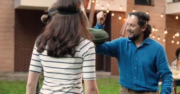 Uomo caucasico in faccia scudo sorridente e incontrare figlio adulto con fidanzata in cortile e saluto con i gomiti. Padre invitante figlia con fidanzato per la cena barbecue. Concetto di pandemia. — Video Stock