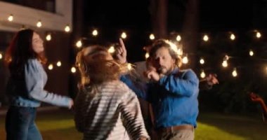 Kafkasyalı mutlu çift geceleri melez arkadaşlar arasında dans edip zıplıyor. Akşam partisinde. Güzel kadın ve yakışıklı erkek dans ediyor ve çok ırklı insanlarla eğleniyor. Kutlama konsepti.