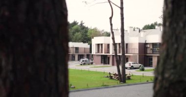 Kenar mahallelerdeki büyük, modern ve pahalı gayrimenkul kompleksini ağaçtan seyret. Yarı müstakil evlerden lüks panorama. Dışarı çıkın. Banliyöde oyun parkı olan elit ipotek.