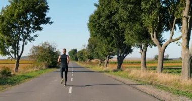 Beyaz tenli yakışıklı, güçlü erkek koşucu yaz günü kırsalda koşuyor. Çekici sporcu adam dışarıda koşuyor. Spor konsepti. Sporcu atlet. Sabah doğası. Arka plan.