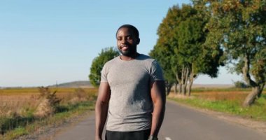 Afrika kökenli Amerikalı yakışıklı güçlü erkek koşucunun portresi yaz günü kırsalda duruyor. Çekici sporcu adam dışarıda koşuyor. Spor konsepti. Sporcu atlet. Sabah doğası.