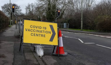 Geçici sarı yön işareti yeni açılan Covid-19 Aşılama Merkezi 'nin yolunu gösteriyor. Kaldırıma ve yola yerleştirilmiş. Kum torbası ve koni ile. Açık yol. Metin için alanı olan manzara resmi. İngiltere.