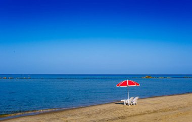 Bich sandalyeleri ve şemsiyesi ıssız bir deniz kıyısında