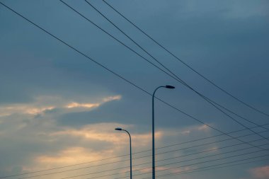 Dramatik Karanlık Gökyüzüne Karşı Ampul direklerinin ve Elektrik kablolarının Silüetleri.