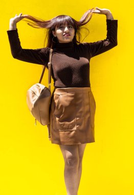 Latin ve esmer kadınlar, gülümsüyorlar, sarı arka planda günlük kıyafetler giyiyorlar.