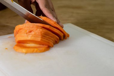 Tahta üzerinde, tahta bir masada taze papaya kesen bir adam..