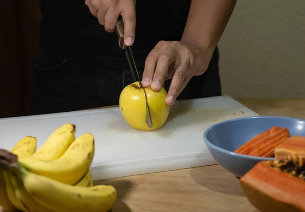 man cutting fruits on a cutting board