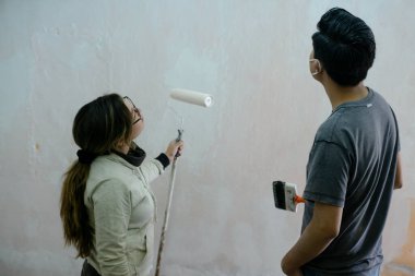 Duvarı boyayarak başardıkları işe hayran olan genç bir çift.
