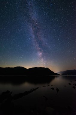 İngiliz Lake Bölgesi 'ndeki Ullswater üzerindeki Samanyolu Glenridding ve Patterdale' den gelen ışık kirliliği şelaleleri arasında parlıyor.